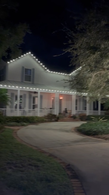 Warm white Christmas lights tracing the roofline and porch of a Florida home
